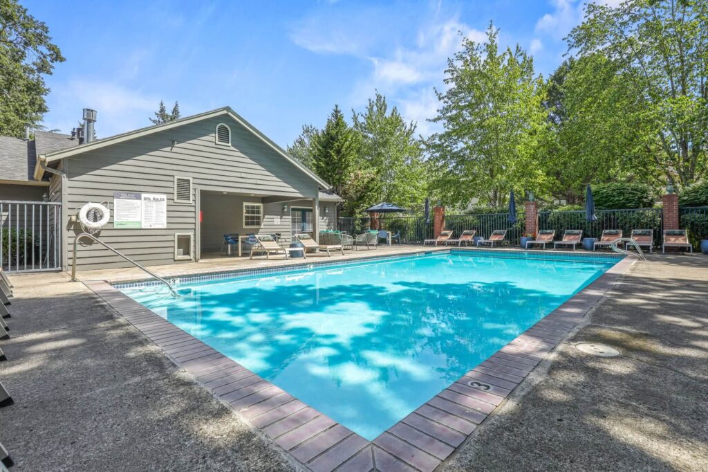 swimming pool with lounge chairs on patio, next to leasing office
