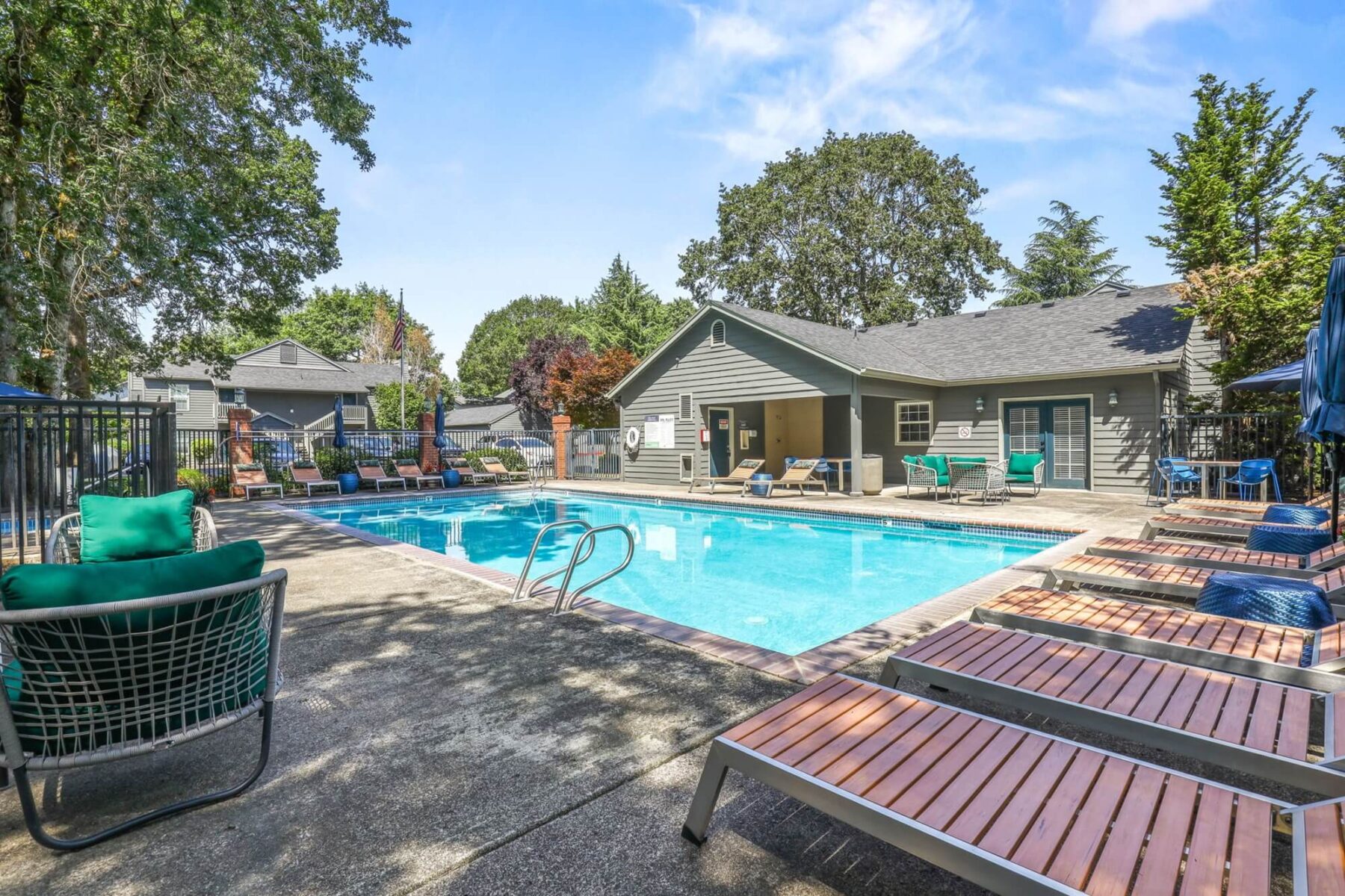 swimming pool with lounge chairs on patio, next to leasing office
