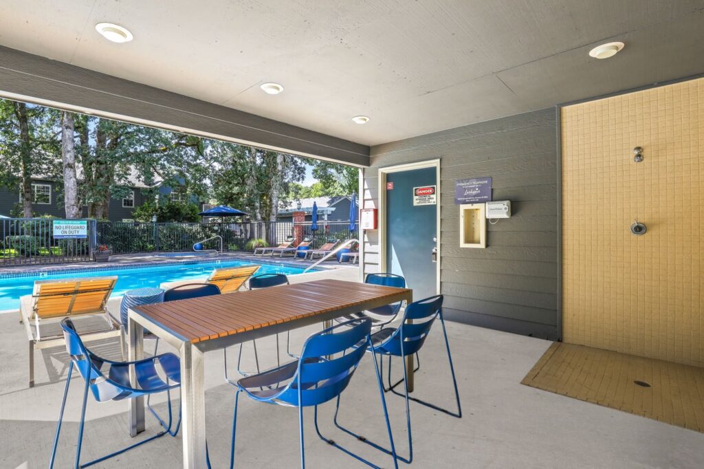 covered seating area next to swimming pool with outdoor shower