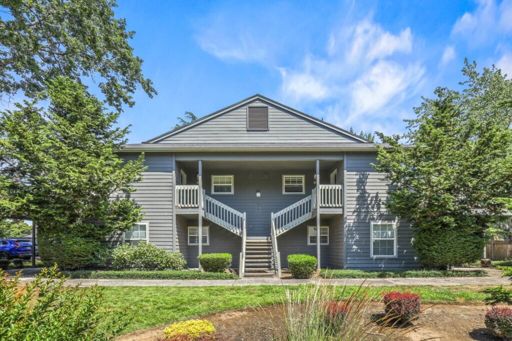 two story apartment building with exterior entrance and staircase to pathway